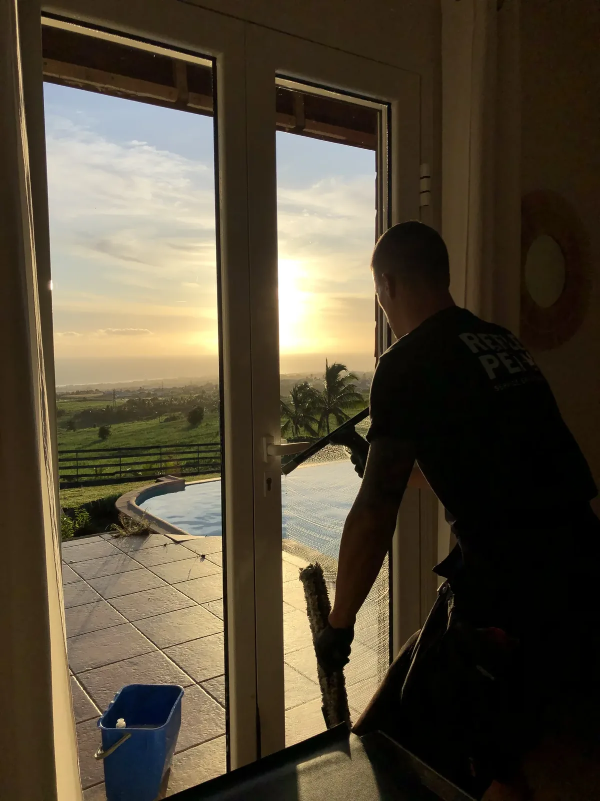 Nettoyage d'une baie vitrée au coucher du soleil à La Réunion